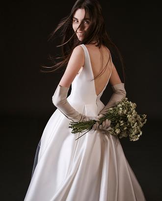 Bride in white Vera Wang wedding dress with low back detail holding white and green bouquet